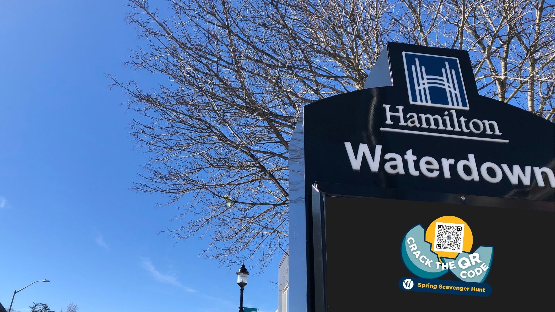 Waterdown Village Sign with Cracked QR Logo against a blue sky